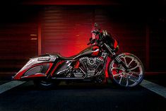 a red and black motorcycle parked in front of a building at night with the lights on