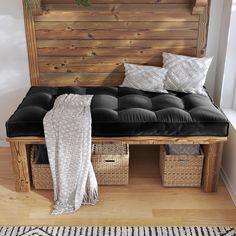 a bench with two baskets underneath it and a blanket draped over the seat on top