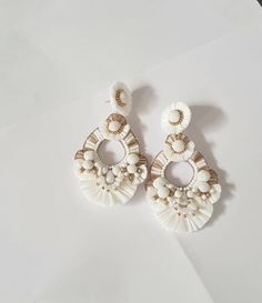 "Boho White and Gold Raffia embellished statement medium size earrings. The earring is hand embroidered using various elements like Raffia, handmade silk pompoms, faux pearl, glass beads, and much more material. This lightweight medium size Raffia white with gold accent earring is a piece of perfect wedding jewelry. The Earrings measure about approx. 2.75\" long and 2.10\" wide. PS: Carnation jewelry is handmade & handcrafted in India hence there is a possibility of a slight or small imperfe Bohemian Handmade Tassel Earrings For Wedding, Handmade Dangle Tassel Earrings For Wedding, White Tassel Earrings For Party, White Tassel Chandelier Drop Earrings, White Beaded Earrings For Summer, Handmade Tassel Earrings For Wedding, Elegant Beaded Earrings For Summer Beach, Elegant Beaded Earrings For Beach In Summer, Elegant Beaded Earrings For Beach Summer