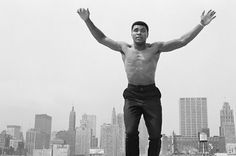 a shirtless man jumps into the air on top of a skateboard in front of a cityscape