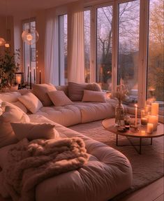 a living room filled with lots of furniture next to tall windows covered in white curtains