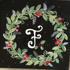 a painted monogram with holly leaves and berries in the center on a black background