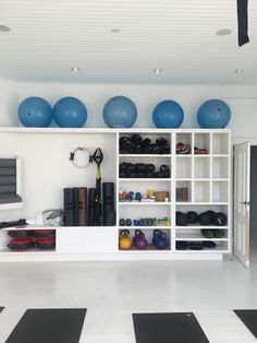 a room filled with lots of exercise equipment and blue balls hanging from the wall above it