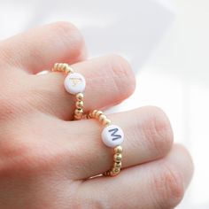 Beautiful beaded Ring with acrylic letters strung on an elastic cord. C U S T O M I N I T I A L ∙ R I N G ----------------------♡--------------------- M A T E R I A L S: * Ball: 18k Gold Plated over Brass * Beads gold: 3 mm * Letters: 7mm * It is made with stretchy elastic string that is very good quality!! -----------------------♡-------------------- SIZE * Adjustable Range US 6 - 8 - 9 ------------------------♡-------------------- H O W T O O R D E R 1.) Choose the Option in the drop down menu Trendy Round Jewelry With Letter Beads, Minimalist Letter Beads Jewelry For Friendship, Minimalist Personalized White Initial Ring, Adjustable Initial Ring, Minimalist Jewelry With Letter Round Beads, Minimalist Jewelry With Round Letter Beads, Adjustable White Initial Ring As A Gift, Adjustable White Initial Ring Perfect For Gifts, Gold Letter Necklace