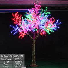 the tree is decorated with colorful lights and has pink flowers on its branches, as well as green leaves