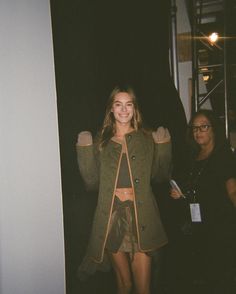 a woman standing in front of a door with her arms up and smiling at the camera