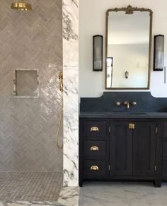 a bathroom with marble counter tops and gold fixtures on the shower wall, along with a large mirror over the sink