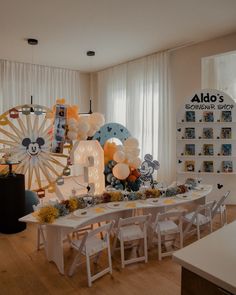 a room filled with lots of balloons and pictures on the wall next to a table