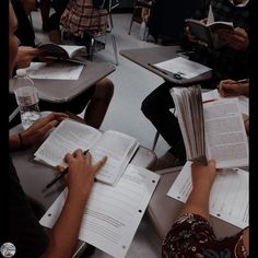 several people sitting at desks with open books in front of them and writing on notebooks