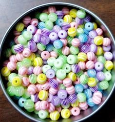 a bowl filled with colorful beads on top of a wooden table