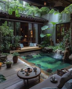 an indoor swimming pool surrounded by greenery and potted plants in the middle of a patio