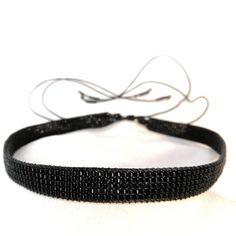 a black beaded headband is shown on a white surface, with the string attached to it