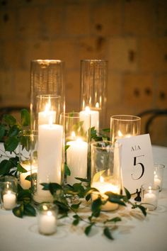 candles and greenery are arranged on a table with a sign that says 5 in front of them