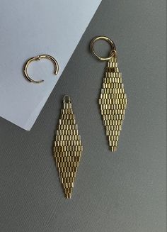 two pairs of earrings sitting on top of a table