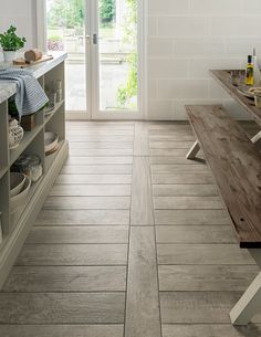 a kitchen with white walls and wooden floors, an open door leading to the outside