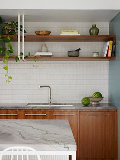 a kitchen with marble counter tops and wooden cabinets, along with open shelving above the sink