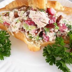 a white plate topped with a sandwich filled with meat and veggies next to parsley