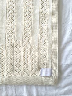 a white knitted blanket sitting on top of a bed