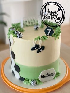 a birthday cake is decorated with black and white soccer balls, green grass, and the number seven