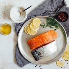 salmon and lemons are on a plate with salt, pepper, mustard, and seasoning