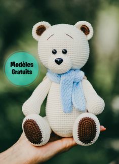 a crocheted white teddy bear wearing a blue scarf