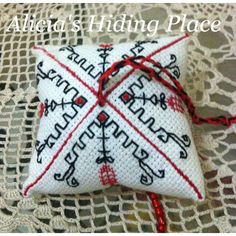 a white pillow with red thread tied to it on top of a lace doily