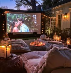 an outdoor movie is set up with candles and blankets