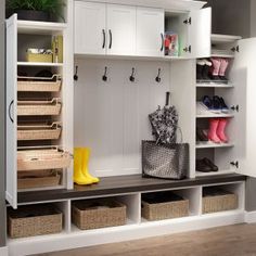 a well organized entryway with white cabinets and baskets on the bench, yellow rubber boots