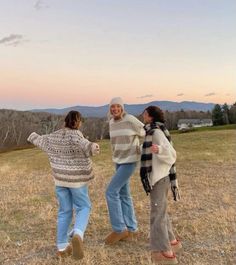 three women standing in a field at sunset