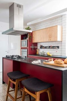 a kitchen with two stools next to the counter and an oven in the background