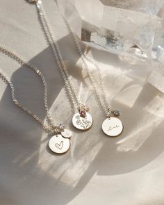 Create a polished palette of togetherness and keep your kin close to heart. Choose from over 130 illustrative symbols for your main pendant, plus a subtle birthstone charm to represent each of your loved ones! Each piece includes one charm (but you can add up to five). The hue of each gem will softly shift depending on the lighting and angle: a tribute to the beautiful multifaceted nature of family. Add an extra gemstone as your story grows, and check out our journal for more about the symbolism Pink Tourmaline Crystal, Ruby Crystal, White Moonstone, Birthstone, Disc Necklace, Tourmaline Crystal, Birthstone Charms, White Sapphire, Birthstone Necklace