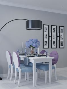 a dining room table with blue chairs and flowers on the table in front of it