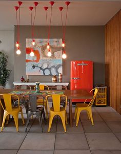 a dining room with yellow chairs and a red refrigerator