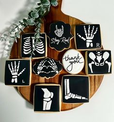 decorated cookies with black and white designs on a wooden platter next to greenery