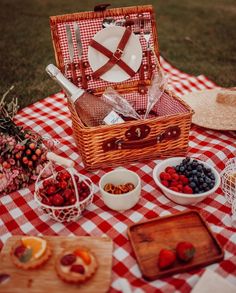 a picnic with fruit and bread on a checkered tablecloth, including strawberries