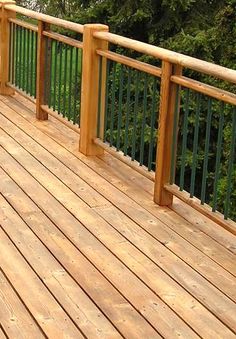 a wooden deck with green railings and trees in the background