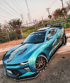 a blue sports car parked in a parking lot next to power lines and telephone poles