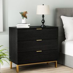 a bedroom scene with focus on the nightstand and bed in the foreground, along with a potted plant