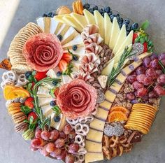 an assortment of cheeses, fruits and meats arranged in a circular arrangement on a table