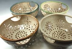 four bowls with holes in them sitting on a table