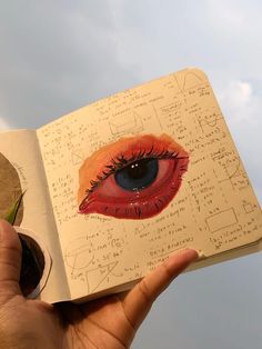 a hand holding an open book with drawings on it