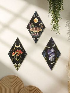 three wall hangings on the side of a white wall next to a potted plant