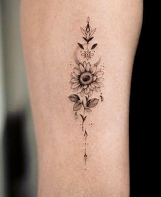 a sunflower tattoo on the back of a woman's thigh, with leaves and flowers