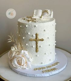 a white cake with gold decorations and a cross on top