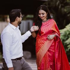 a woman in a red sari and a man in a white shirt are standing next to each other