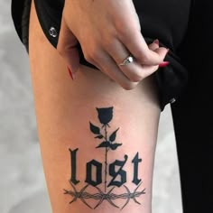 a woman's leg with the word lost written on it and a rose tattoo