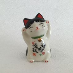 a white and black cat figurine with chinese writing on it's chest