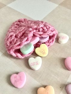 pink crocheted pouch with conversation hearts on checkered tablecloth next to it