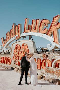 a newly married couple standing in front of the neon sign