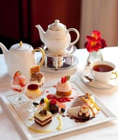 there are many small desserts on the table with cups and saucers around them